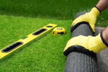 Rolling out artificial turf onto a concrete base